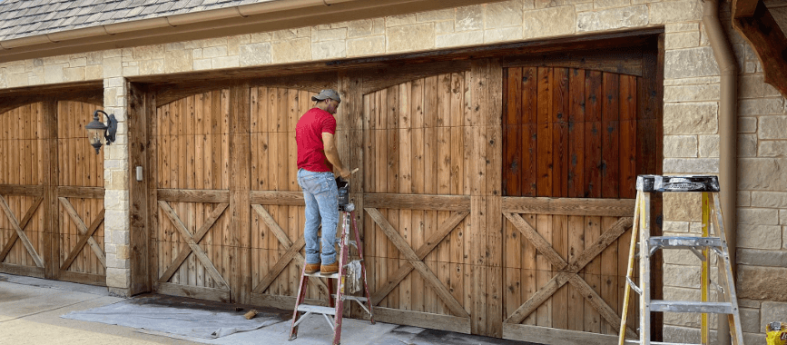 Worker on ladder painting house exterior